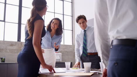 Five-young-professionals-talking-at-a-meeting,-low-angle