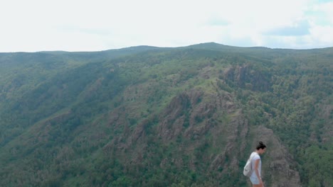 drone fly over impressive mountains with girl on a cliff face, vertigo effect