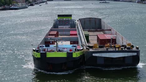 container barge carrying goods and navigating along calm river waters