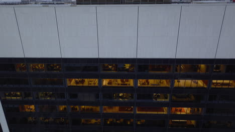 View-into-office-interiors-through-windows.-Ascending-tilt-down-footage-of-business-skyscraper-in-city.-Rising-above-rooftop.-Manhattan,-New-York-City,-USA