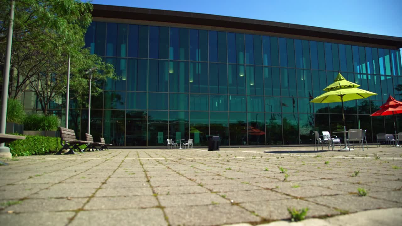 휘트비 공공 도서관 광장은 시골의 나무 벤치에 야외 좌석을 제공하여 캐나다 마을에 자리 잡은 현대 도서관의 외부 관점을 제공합니다.