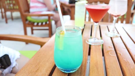 person sipping a blue cocktail at a table