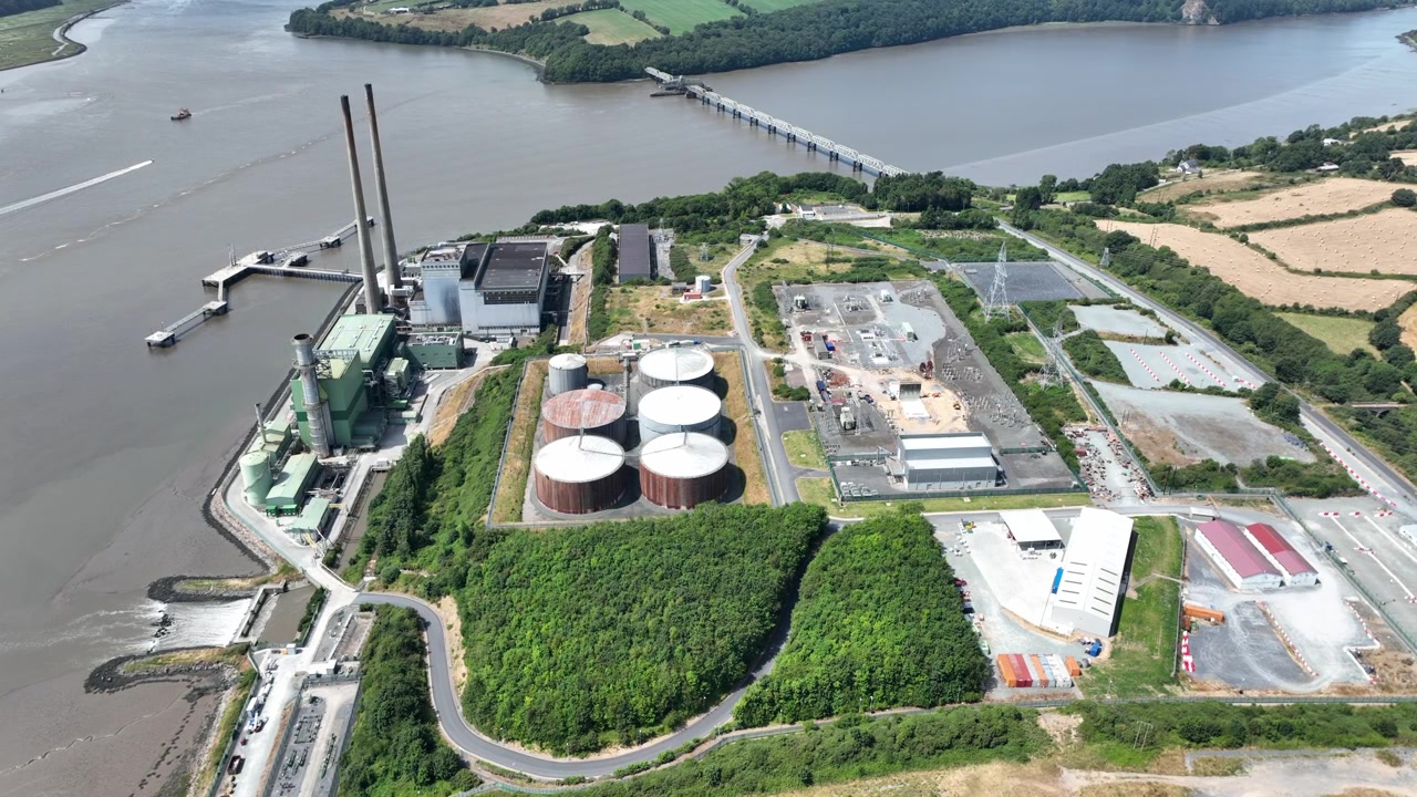 static aerial power station on banks of river,Ultra HD aerial footage of electricity generating station on the River Suir, Wexford. infrastructure with tranquil river, green countryside