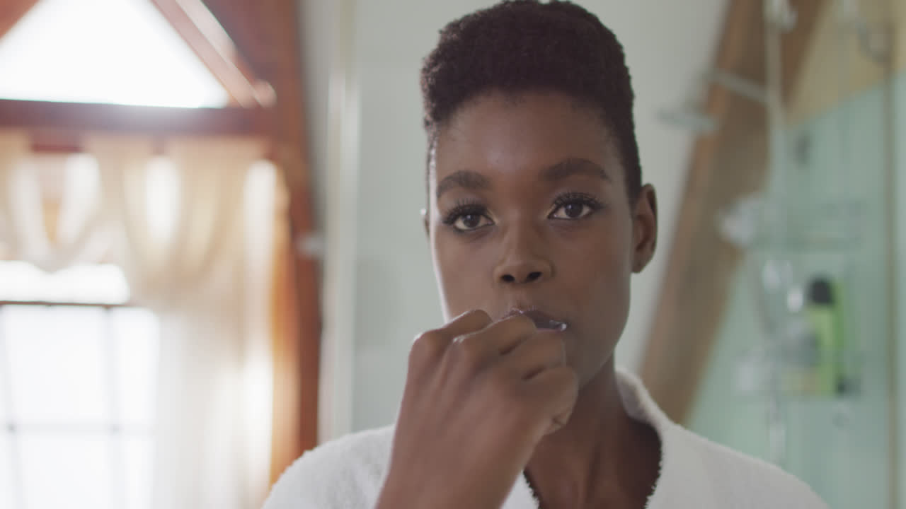 African american attractive woman brushing teeth in bathroom