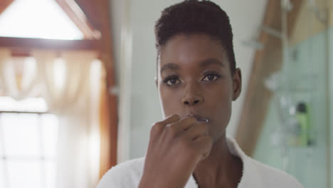 African-american-attractive-woman-brushing-teeth-in-bathroom