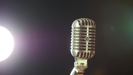 A-vintage-elvis-microphone-in-front-of-a-dark-background-with-a-stage-light-source-in-the-corner