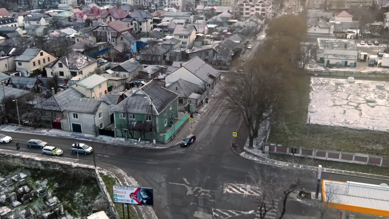 Aerial drone view of a residential distict in Chisinau, Moldova. Multiple buildings, road, cemetery on the left, Cloudy weather, bare trees, winter