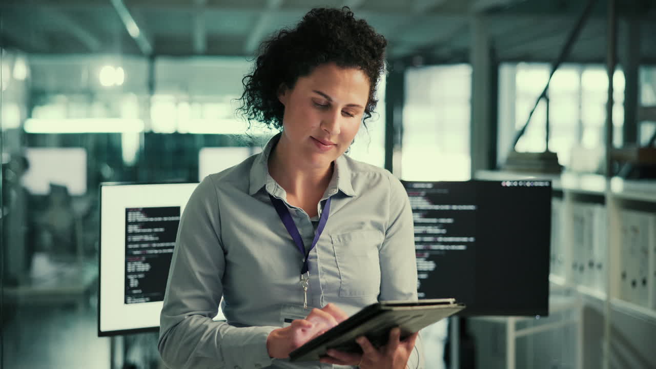 una mujer sonriente en una oficina, trabajando en una computadora portátil.