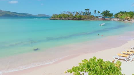 la gente nuota in acqua turchese e sedie a sdraio sulla spiaggia sabbiosa di playa rincon in repubblica dominicana