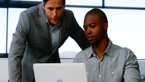 Business-executives-discussing-over-laptop