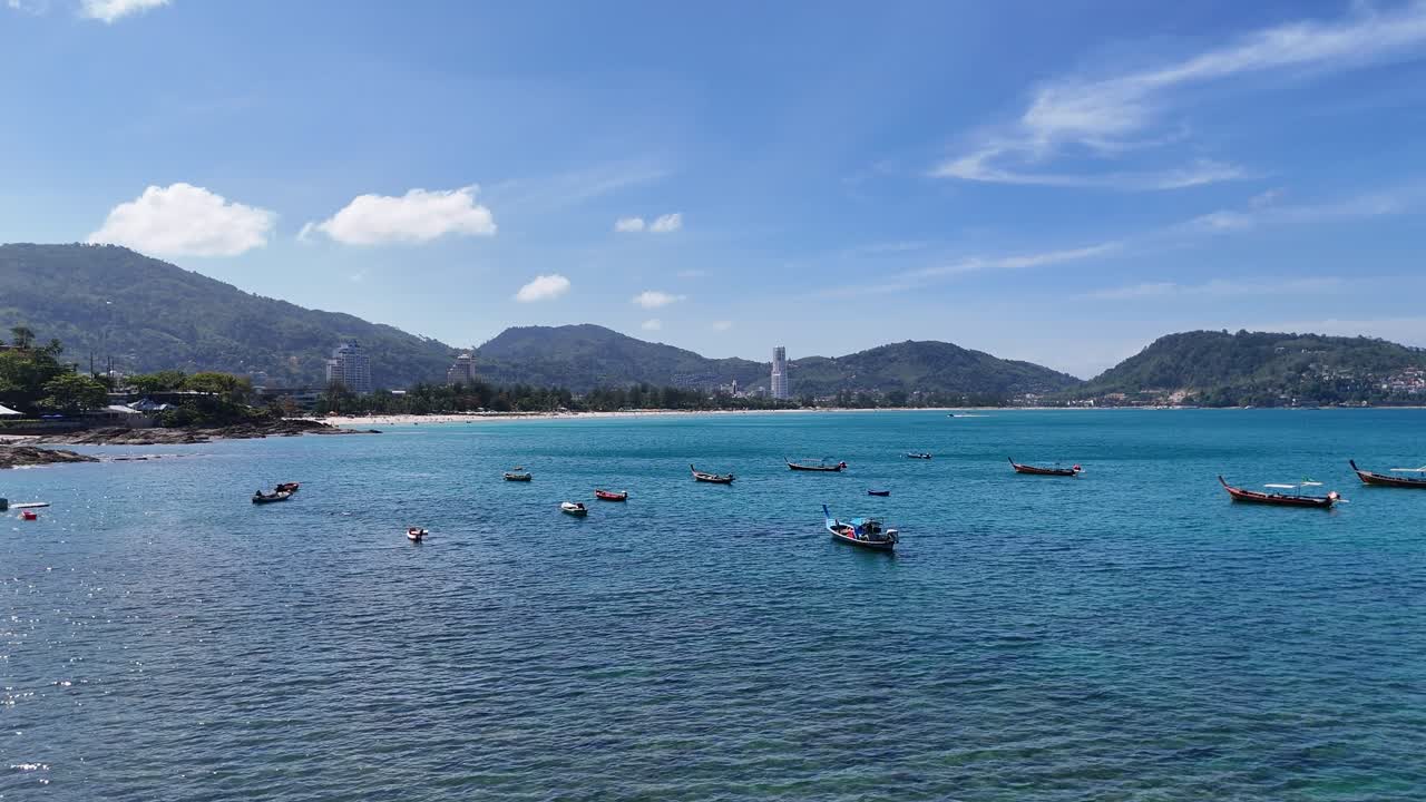 밝은 하늘 아래 울창한 언덕에 둘러싸인 안다만 해의 은 파란 물에서 떠다니는 배의 조용한 풍경