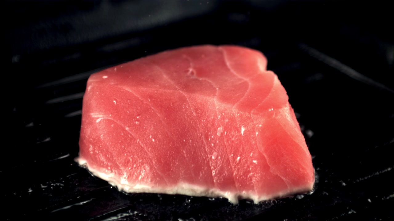 Bistecca di tonno fresco che sfrigola su una padella grill calda