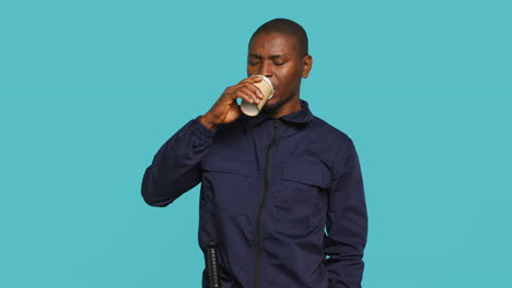 el agente de seguridad usa la taza de café para mantenerse energizado mientras asegura el puesto.