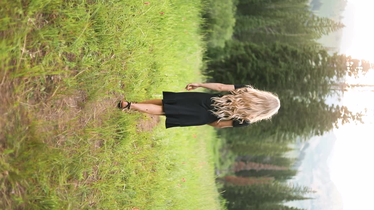 Beautiful Blonde Woman Walking Peacefully in Green Forest, Vertical
