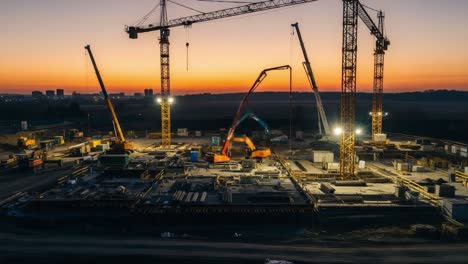 night view of an active construction site with cranes and heavy machinery