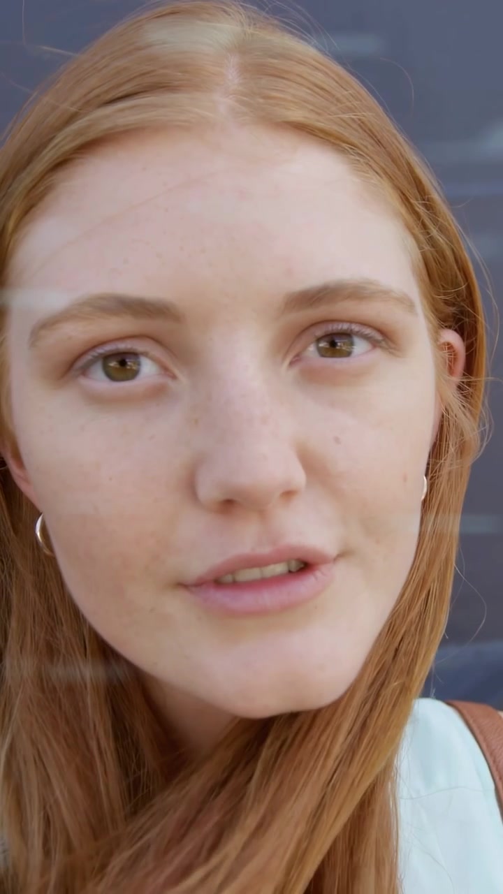 Vertikal video: Kvinde sætter håret, mens et binært overlay stiger op over ansigtet, fastholder blikket til en teknologidemonstration.