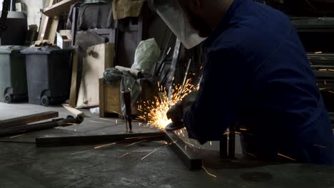 anonymous workman welding metal construction in workshop