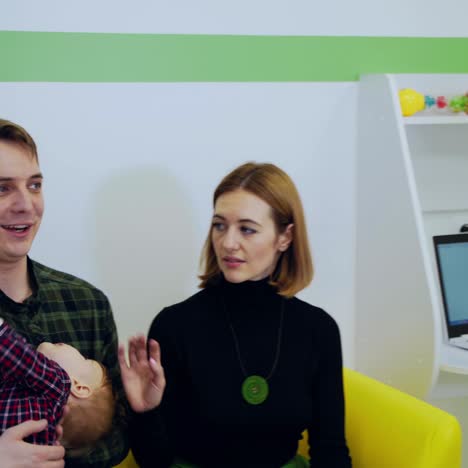 smiling doctor and caring parents in medical office. medical specialist man with stethoscope talking to a young family about baby's heath in kids center.