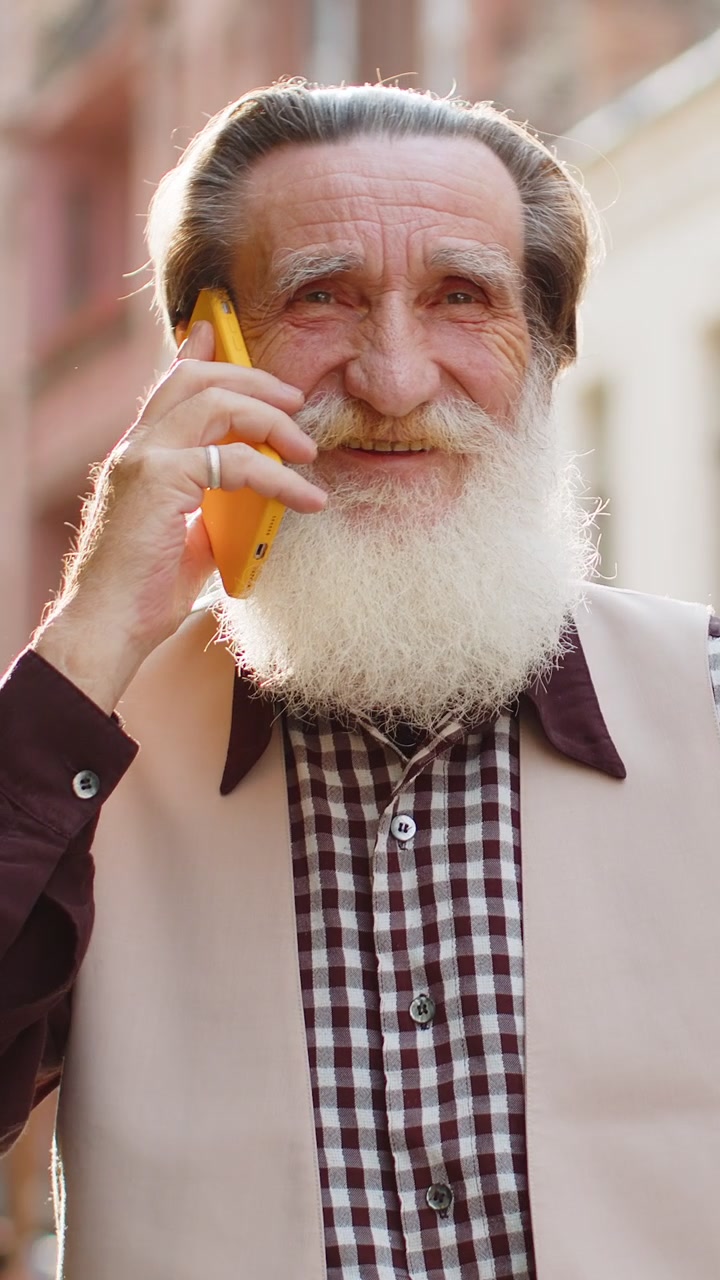 Happy man grandfather having remote conversation talk on smartphone good news gossip in city street