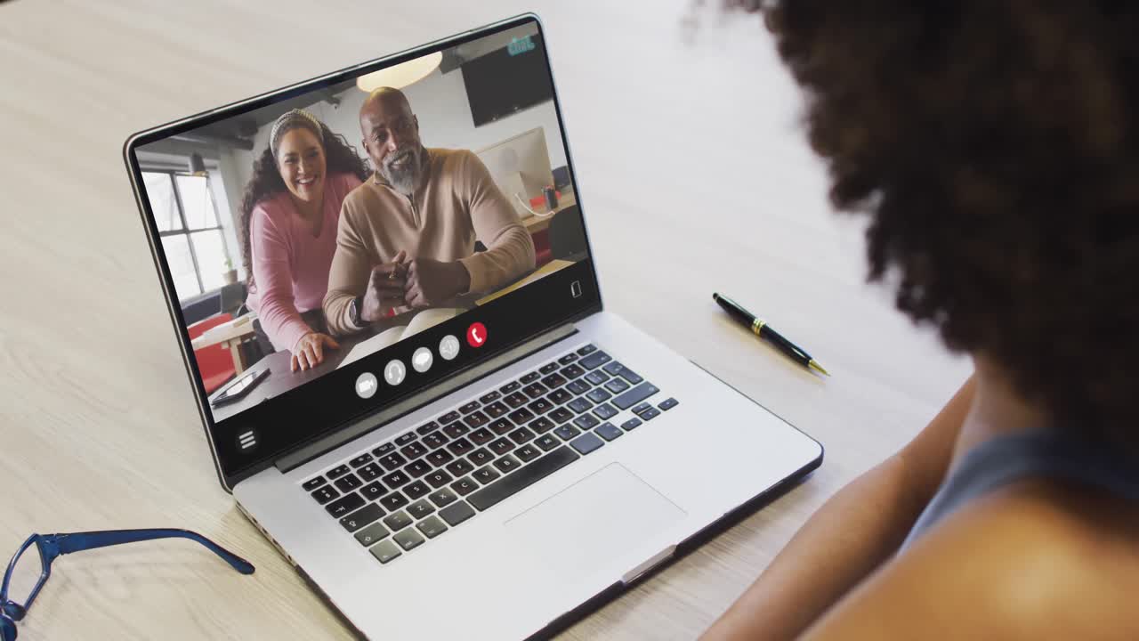 African american woman using laptop for video call, with diverse business colleagues on screen