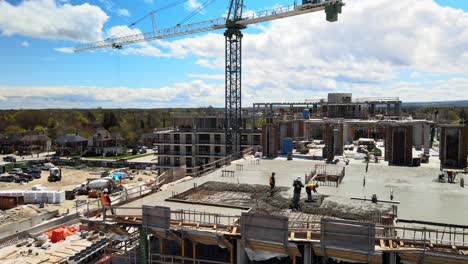 trabajadores de la construcción rastrillando concreto en una construcción de apartamentos