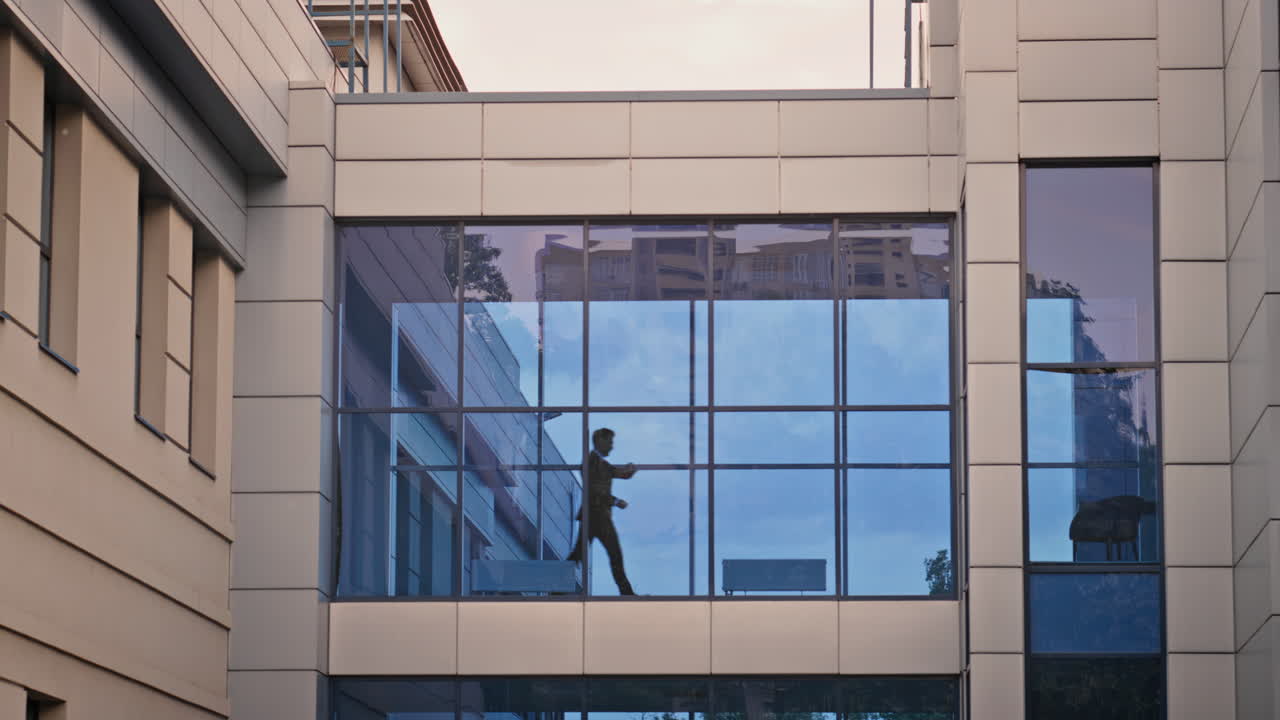Entrepreneur walking across office glass bridge building. Silhouette executive