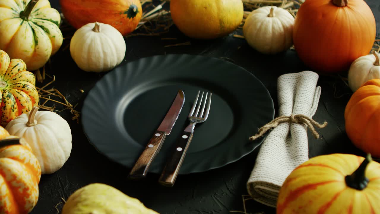 plato negro y cubiertos rodeados de calabazas