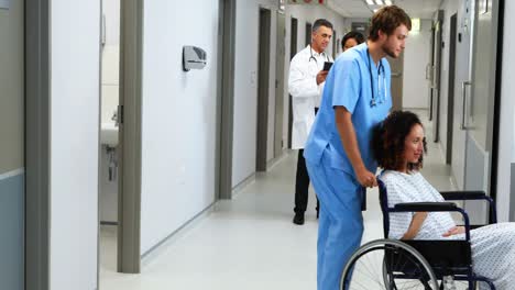 mujer embarazada llevando en silla de ruedas mientras el médico discute en el fondo