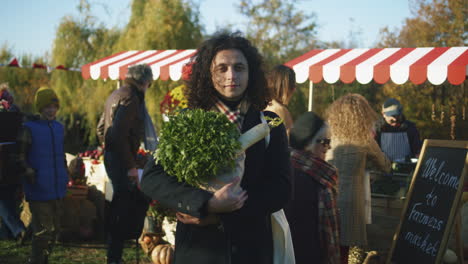 middle aged curly man posing with bag middle aged curly man posing with bag of vegetables or fruits and looks at camera takes care of his health by buying vegetarian organic and healthy products