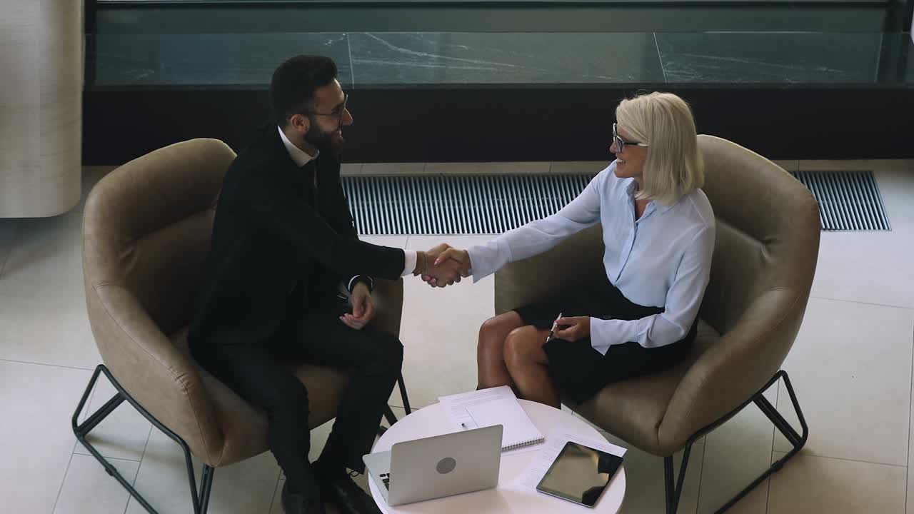 Arabic businessman handshaking mature businesswoman thanking for collaboration