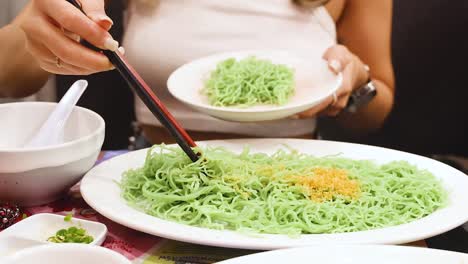 woman prepares and serves green noodles dish