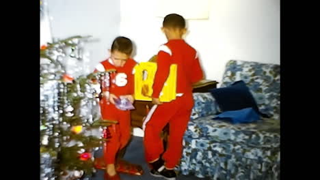young boy opening christmas present in living room. circa usa - 1970s: a young boy excitedly opens a christmas present in a 1970s living room in the usa.