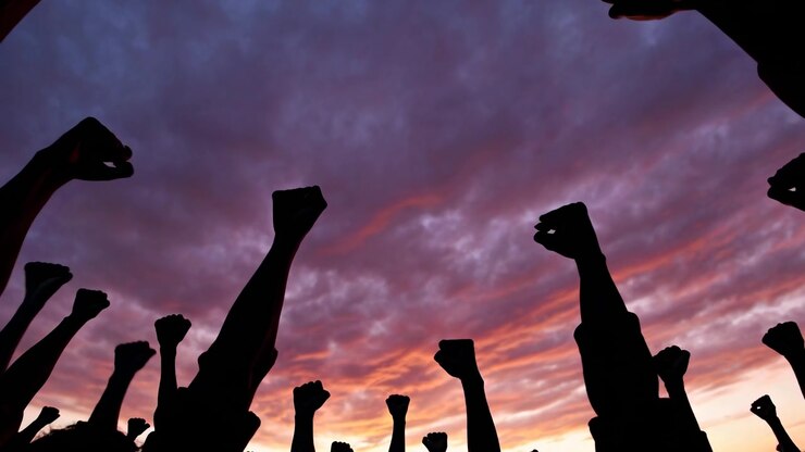 Silhouetted Fists Raised in Protest Against Dramatic Sunset Sky