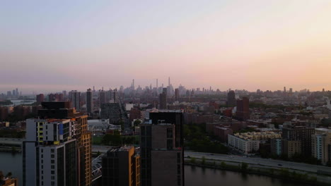 Vista-Aérea-Ascendente-Desde-El-Techo-De-Un-Apartamento,-Revelando-El-Horizonte-Iluminado-Por-El-Sol-De-Harlem-Y-Manhattan,-En-Nueva-York,-Estados-Unidos