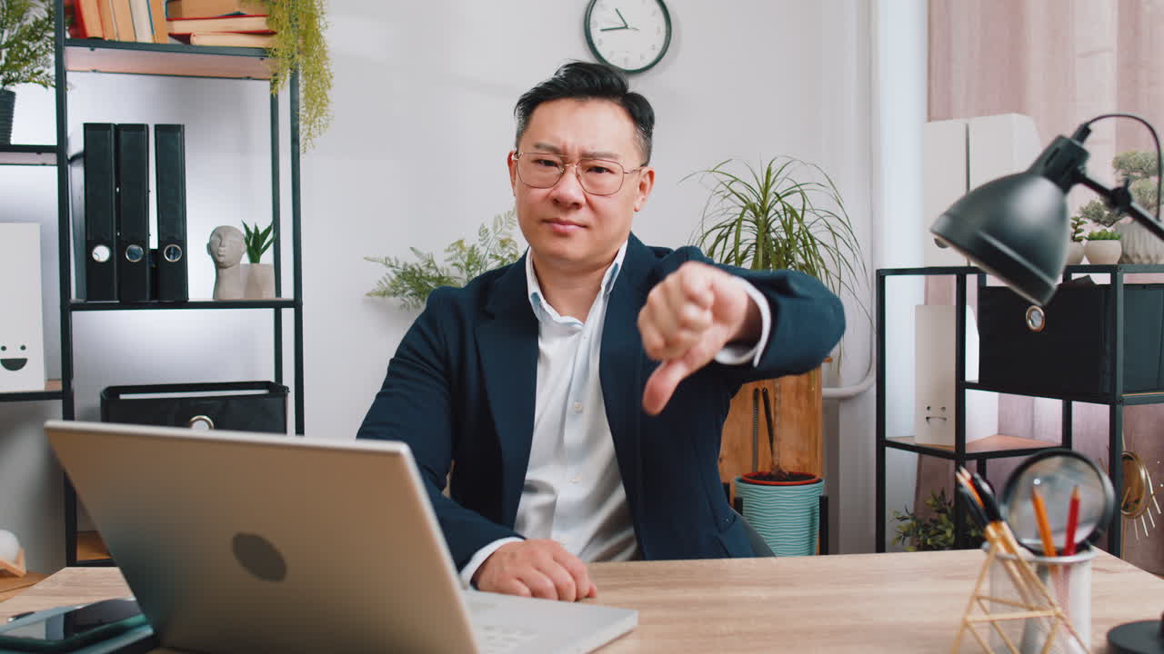 Upset businessman showing thumbs down dislike bad work disapproval dissatisfied feedback at office