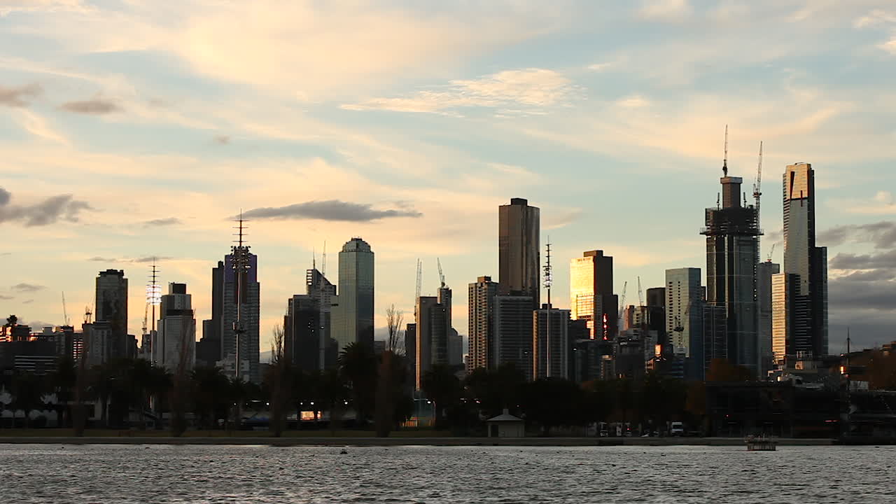 melbourne cbd visto desde el lago albert park, con muchas grúas encima de cada edificio durante las horas del atardecer