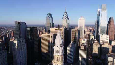 philadelphia city hall tower and bronze statue of william penn. cityscape and beautiful sunset light in background. pennsylvania