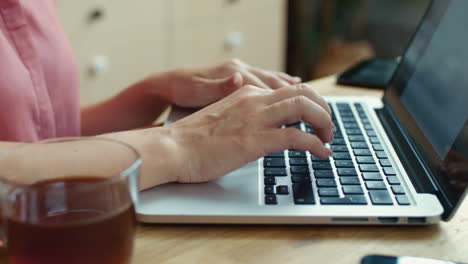 Woman-hands-typing-on-notebook-in-kitchen.-Business-woman-using-laptop-at-home.