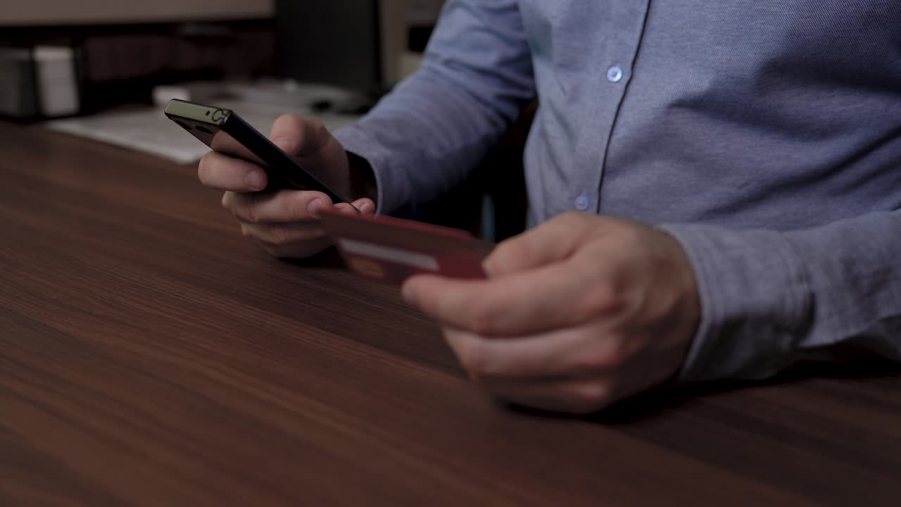 бизнесмен держит мобильный телефон в одной руке и кредитную карту в другой. он использует свою кредитную картку, чтобы заплатить онлайн. слайдер видео.