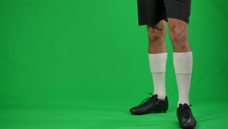 young sportsman jumping up passing football ball at chromakey background. unrecognizable caucasian man making soccer trick on green screen. skill and sport concept.