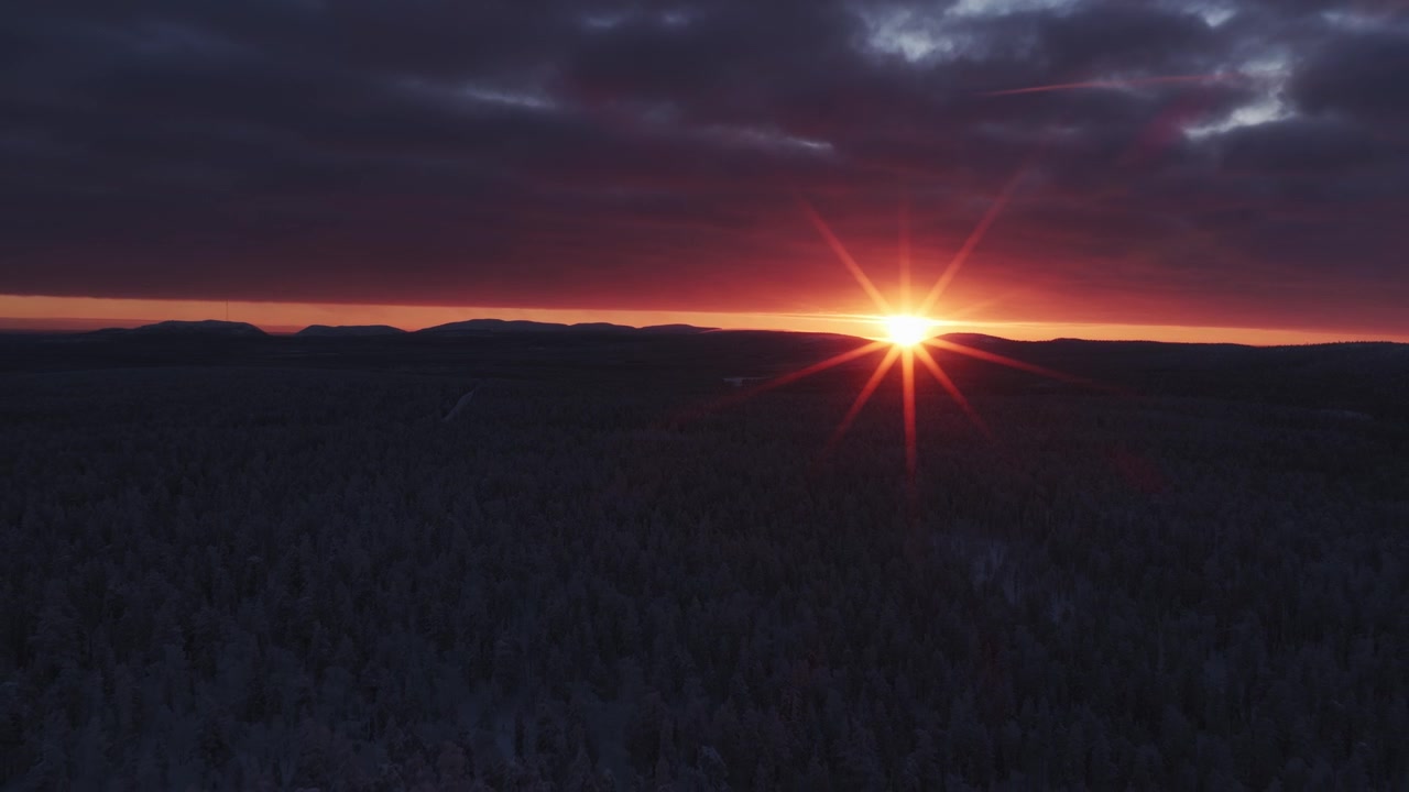Letecký záběr s oddálením úchvatného zimního východu slunce nad národním parkem Pyhä-Luosto.
