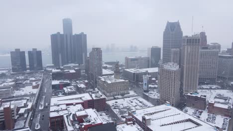 downtown detroit with detroit river in background during snowfall, aerial