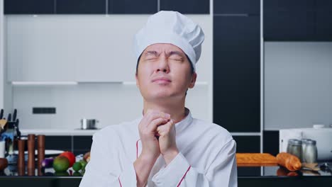 close up of asian man chef praying for something while standing in home kitchen