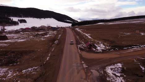 Following-A-Vehicle-Driving-On-Countryside-Road-In-Tsalka,-Georgia-During-Winter-Season---tracking-shot