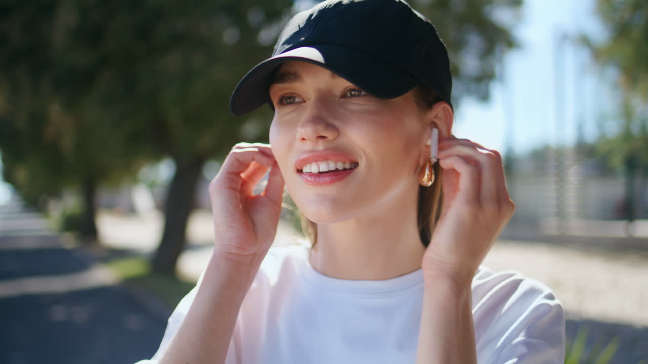 Relaxed woman wearing earphones on sunny street closeup. Lady enjoying music