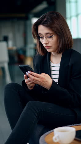 freelancing lady uses her phone typing a message. smiling woman communicating via internet on her gadget. vertical video.