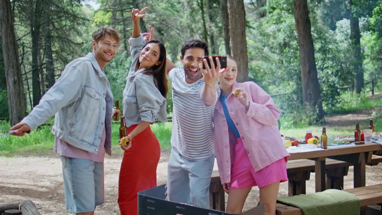Cheerful buddies having fun at park picnic. Smiling group friends taking selfie