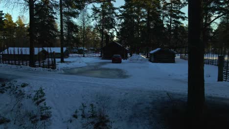 Reveal-Vacation-Log-Cabins-in-Snow-in-Rural-Forest,-Aerial-Rising