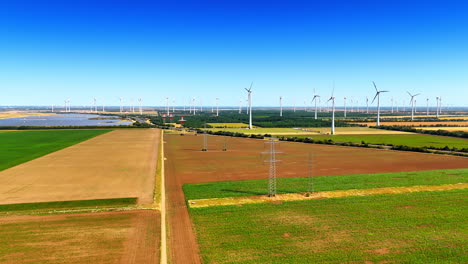 rising over the fields in the rural area. electricity power lines, solar panels and wind turbines located in the countryside. aerial view