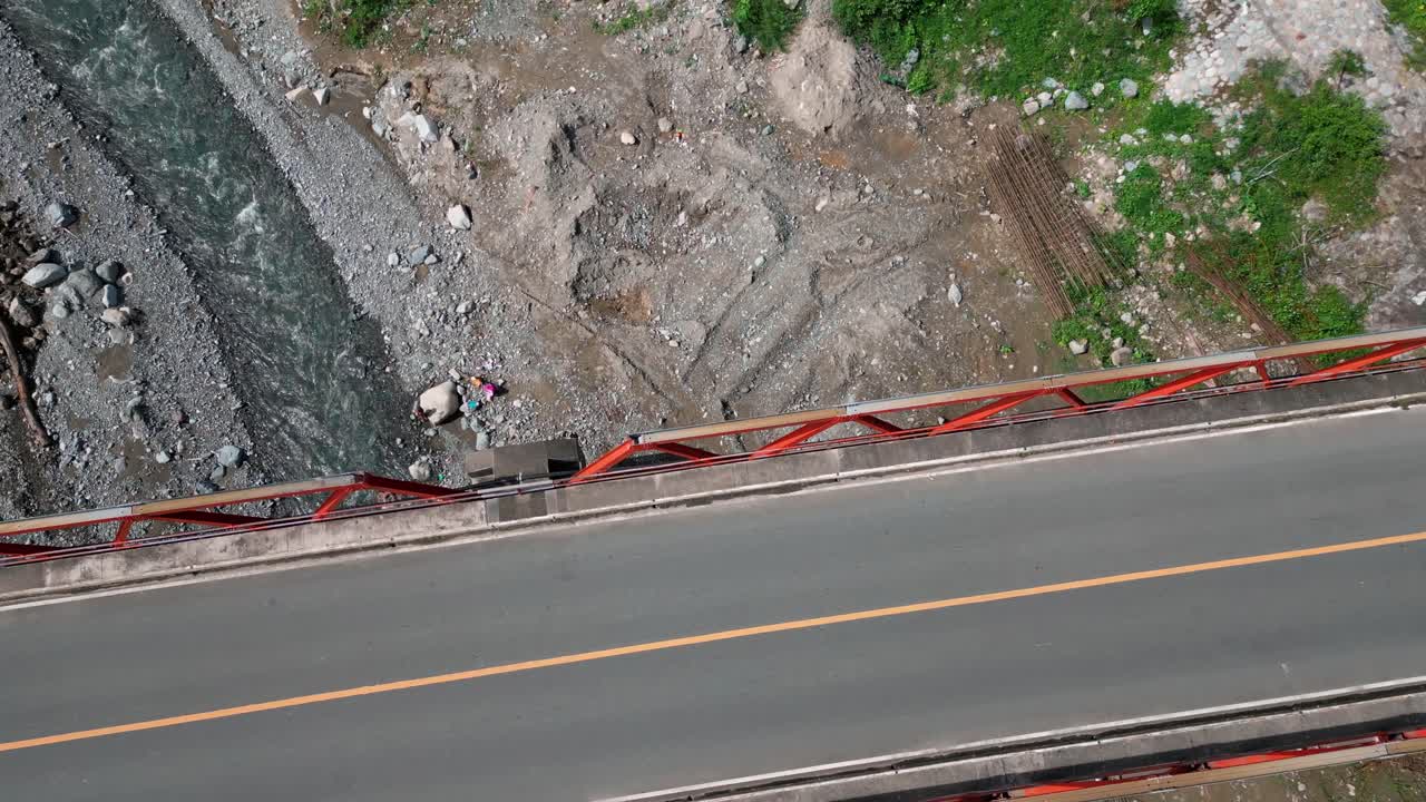 A top aerial view captures a bridge spanning across a river, with the water flowing gently beneath it, creating a peaceful and scenic landscape.